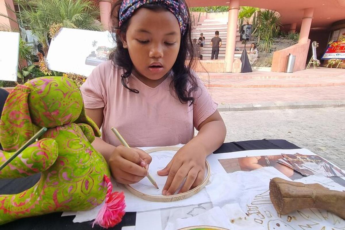 a little girl sitting at a table with a painting