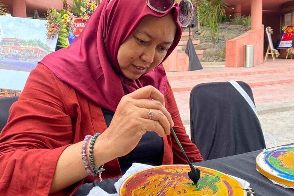 seorang wanita duduk di meja memotong pinggan dengan sudu