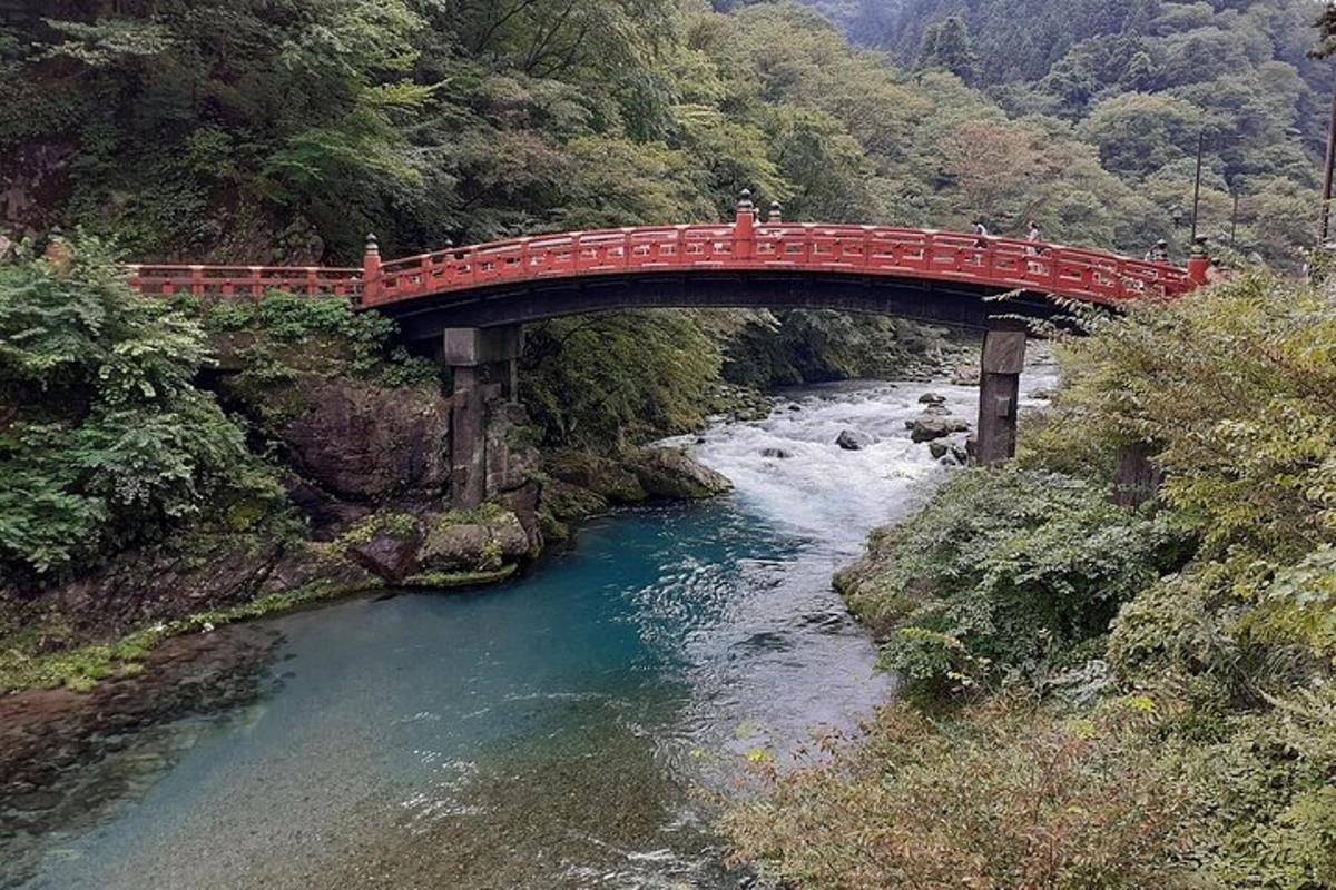 un ponte rosso sopra un fiume con persone sopra