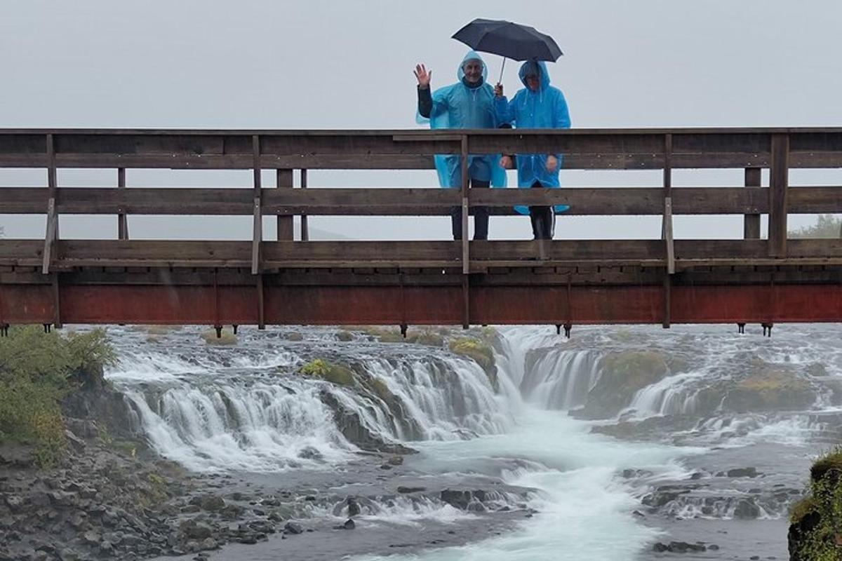 two people standing on a bridge over a waterfall