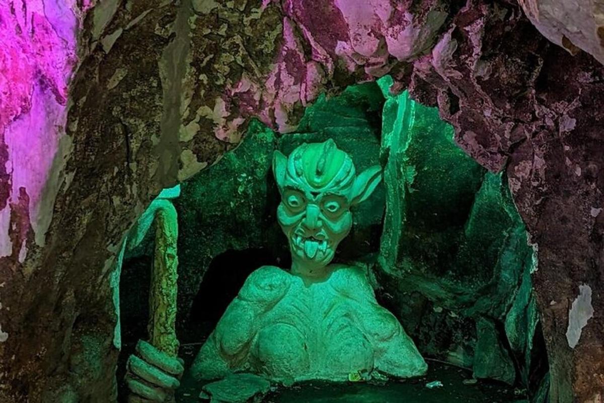 uma estátua verde de uma mulher sentada em uma caverna