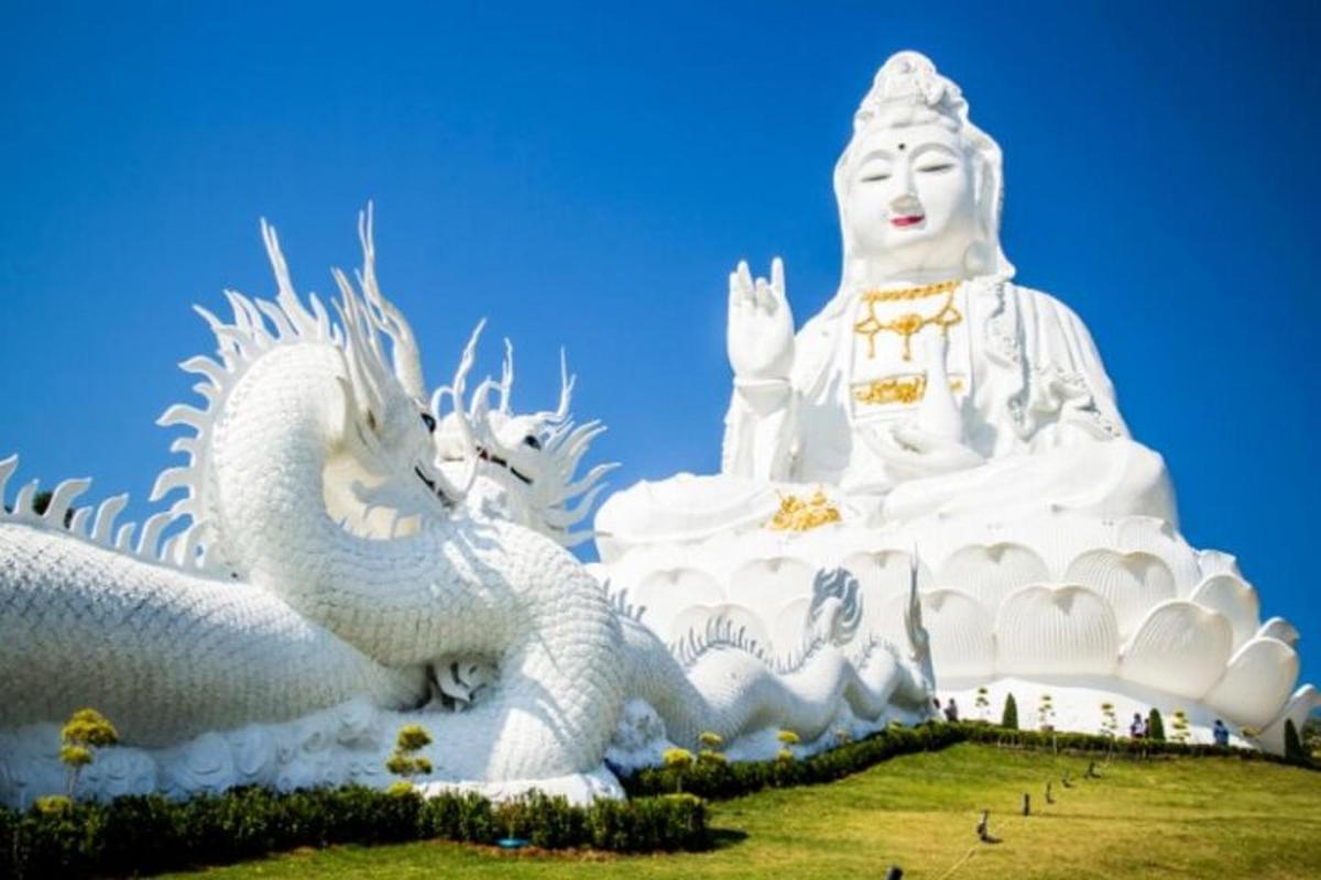 eine große weiße Drachenstatue neben einem großen Gebäude
