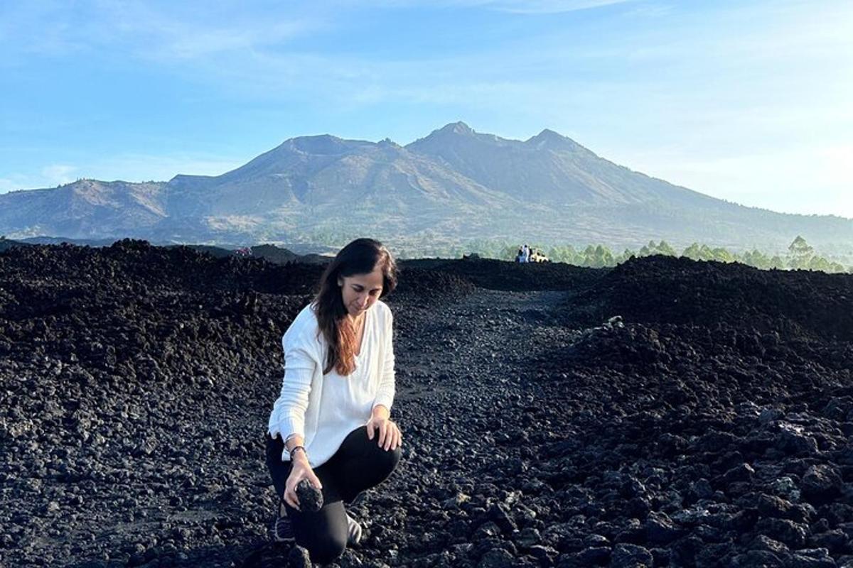 una donna seduta su un mucchio di rocce nere
