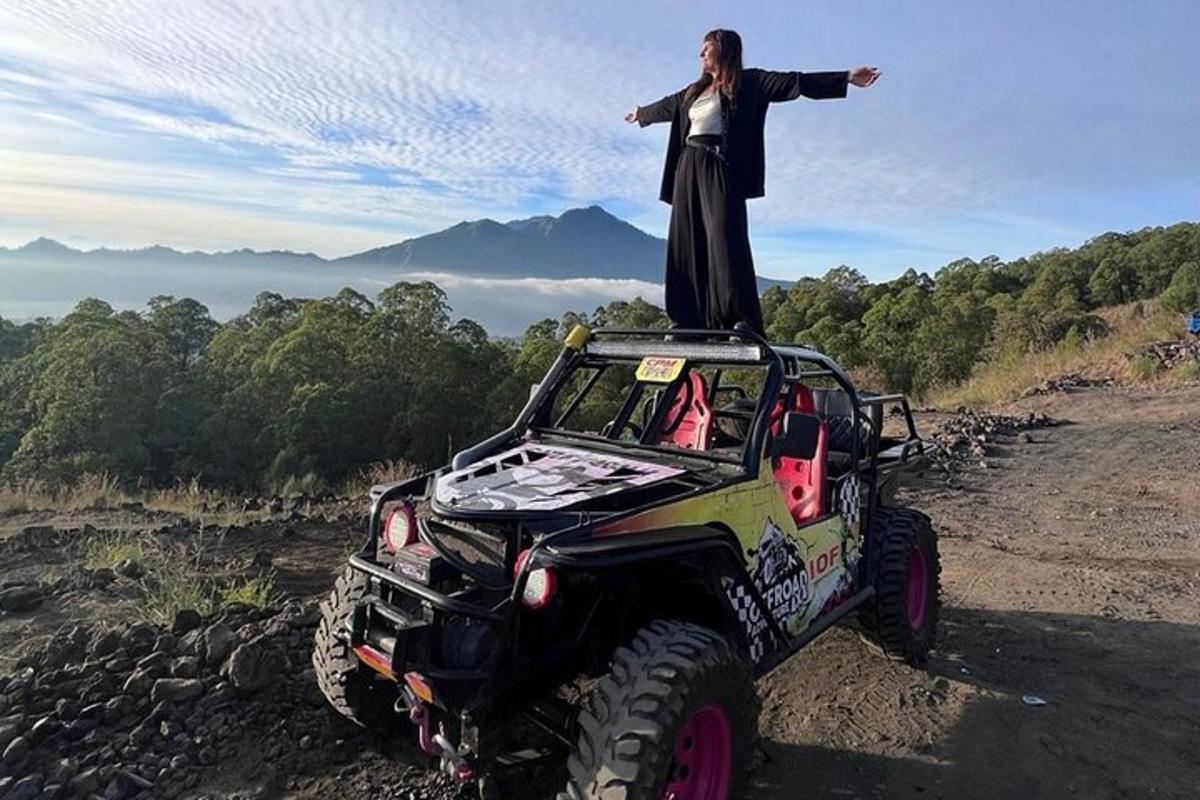 una donna in piedi sul tetto di una jeep con le braccia tese