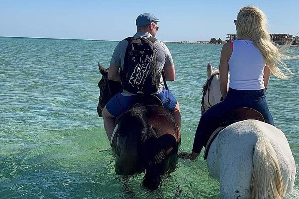 un uomo e una donna a cavallo nell'acqua