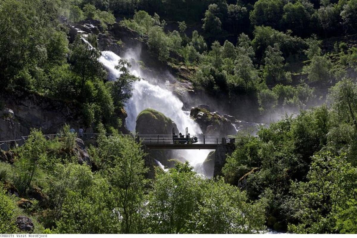 a group of people standing on a bridge over a waterfall