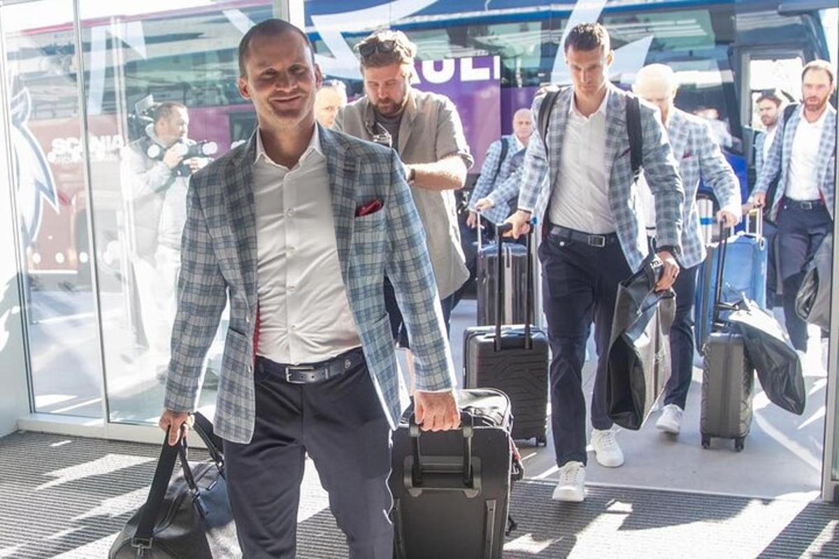 skupina mužů kráčejících se zavazadly na letišti