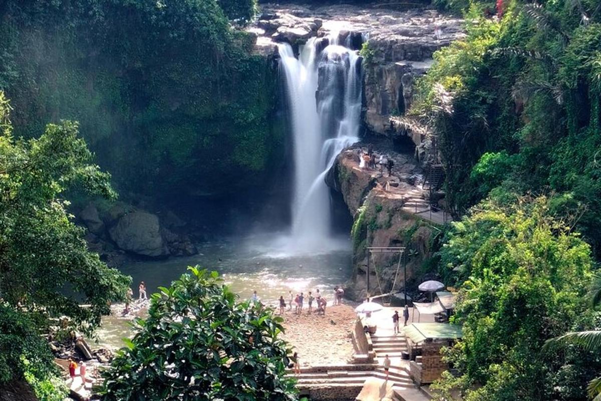 air terjun dengan sekumpulan orang berdiri di hadapannya
