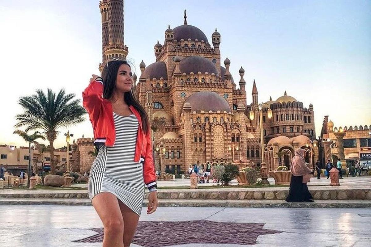 امرأة ترتدي فستانًا مخططًا تقف أمام مبنى