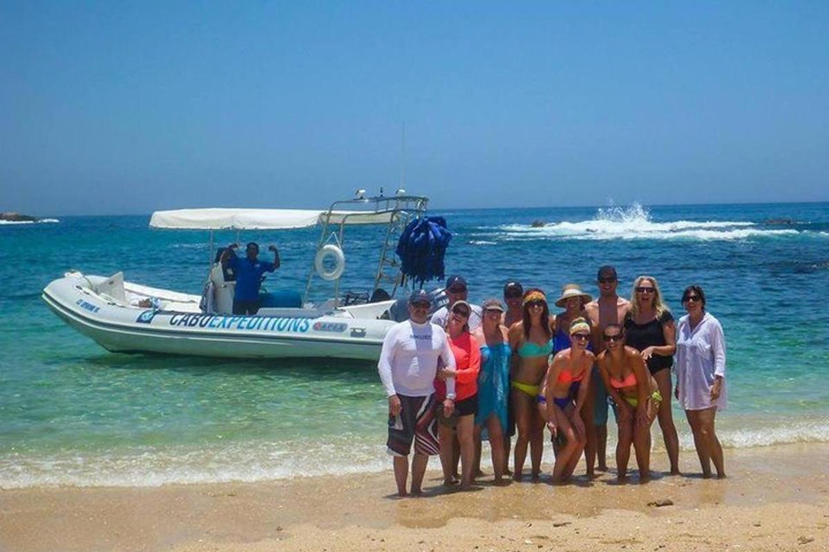 sekumpulan orang berdiri di pantai bersebelahan bot