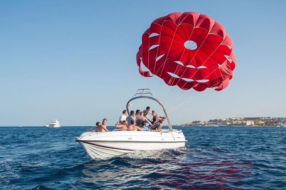 Un grupo de personas en un barco en el agua con un paracaídas.