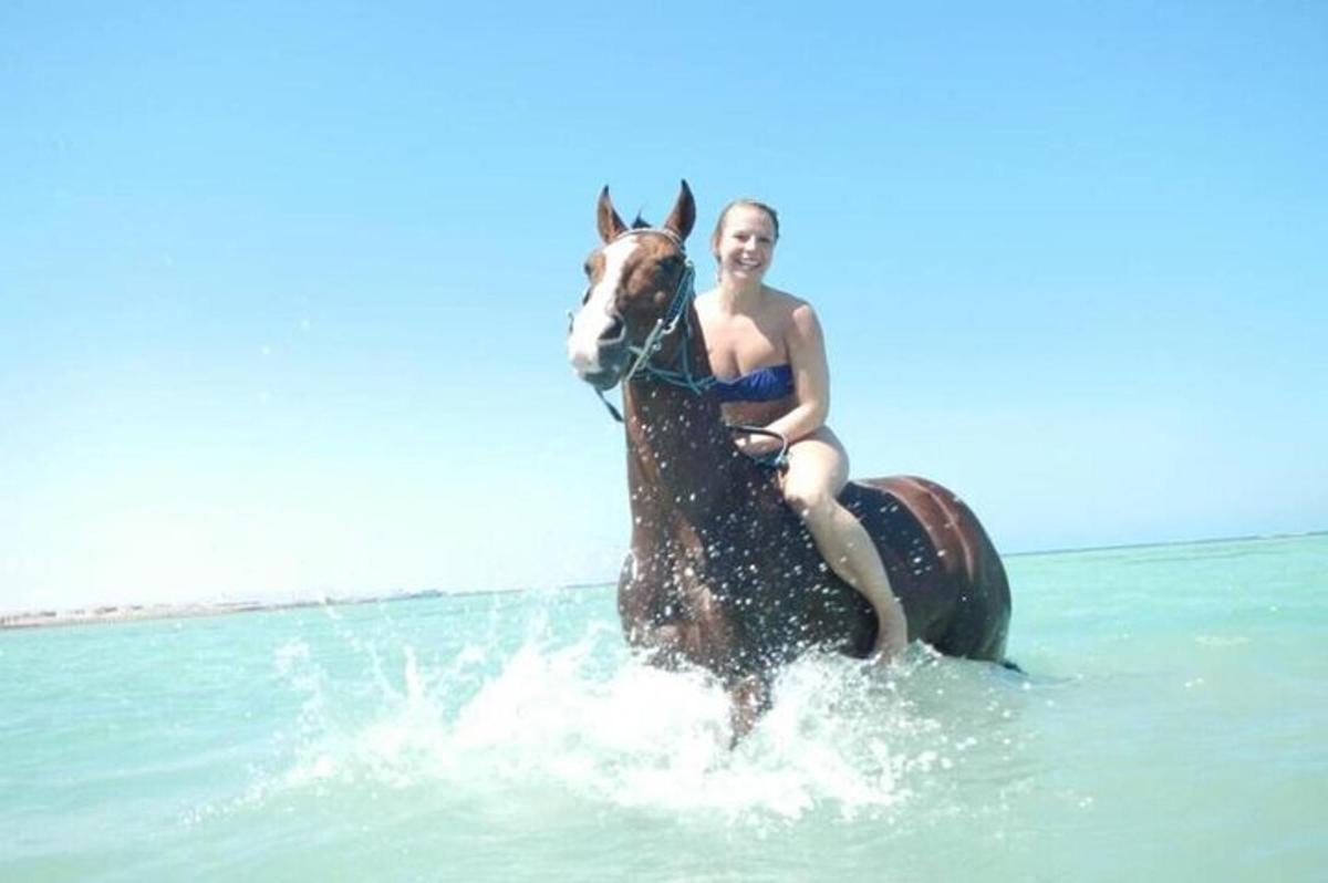 žena v bikinách jedoucí na koni v oceánu