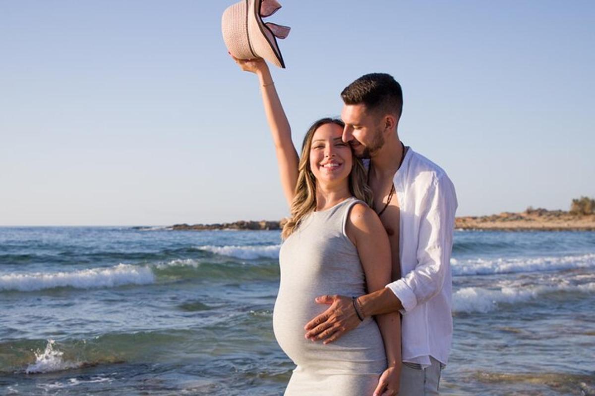 a man and a pregnant woman standing on the beach