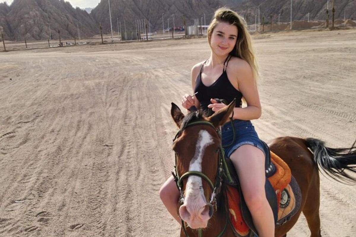 una giovane donna a cavallo sulla spiaggia