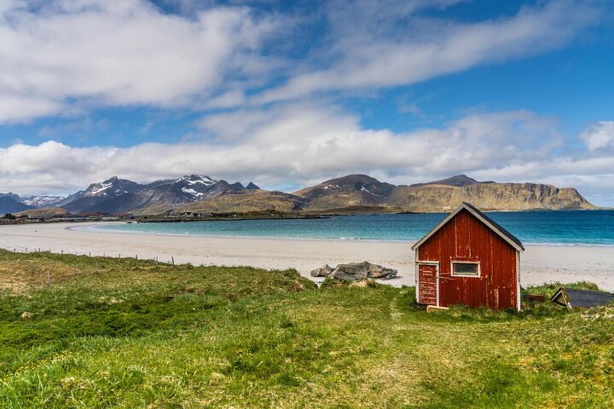 a red house on a beach with mountains in the background
