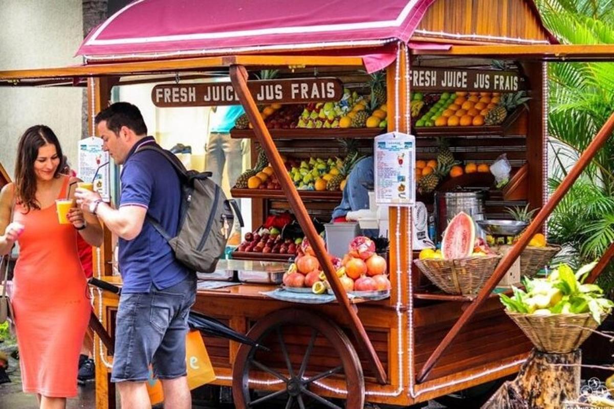 un homme et une femme debout devant un chariot de fruits