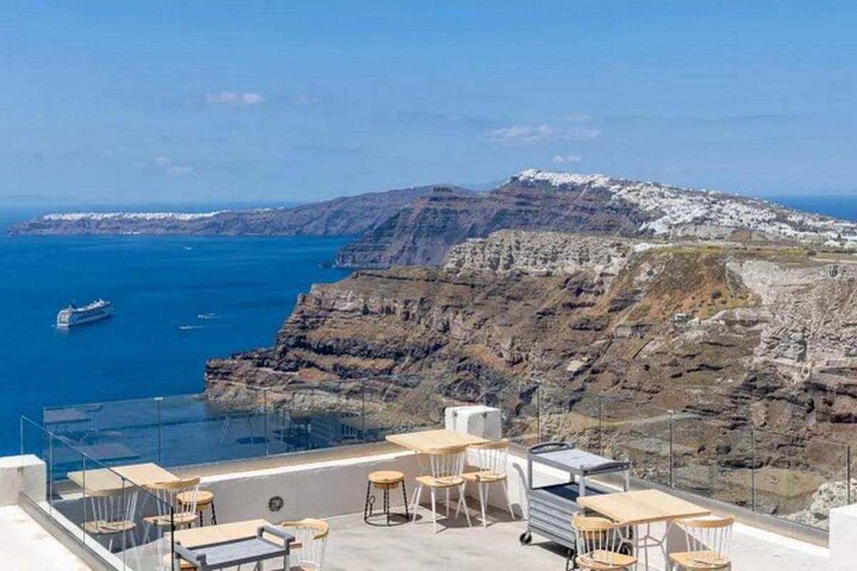 a view of the ocean from a balcony with tables and chairs