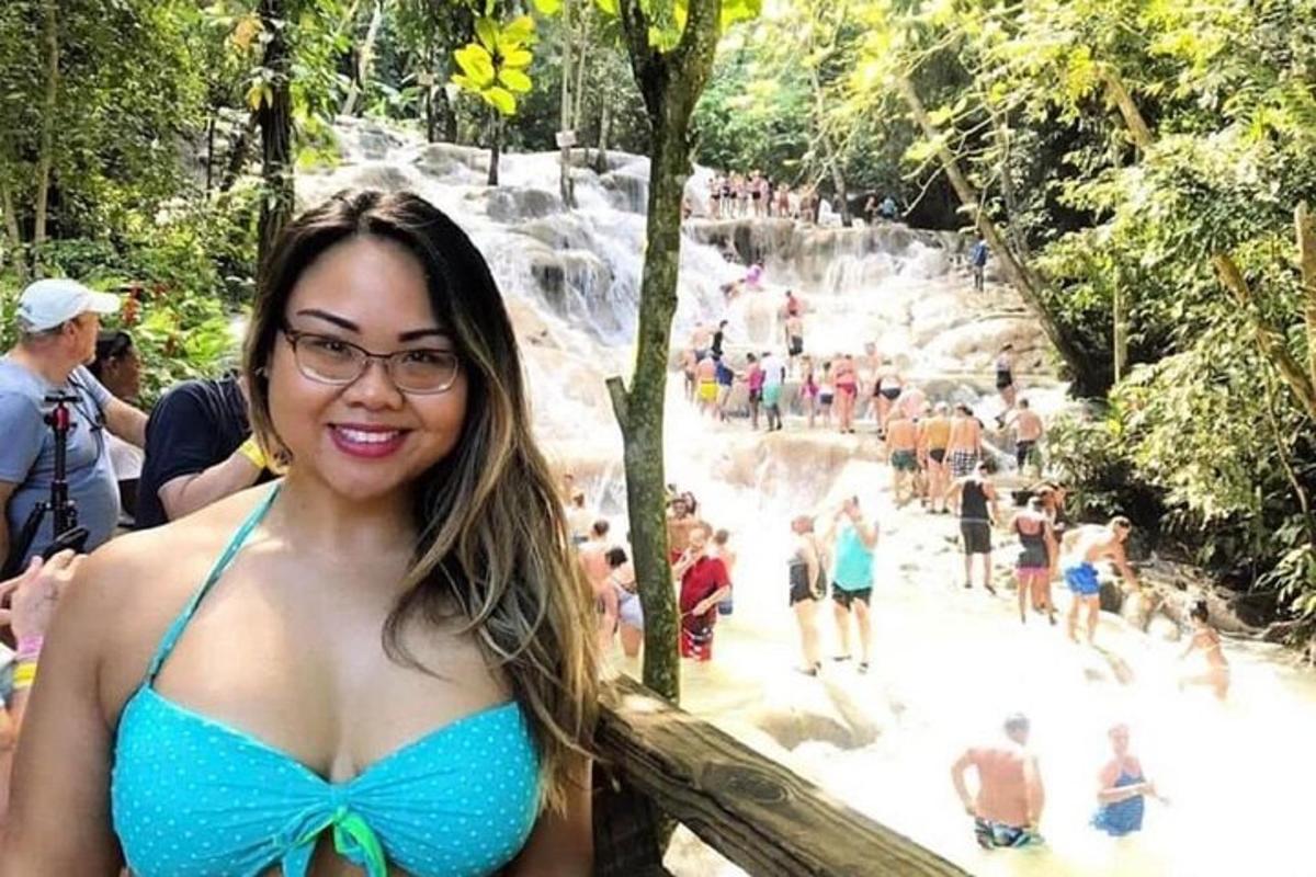 nainen sinisessä bikinissä seisoo vesiputouksen edessä