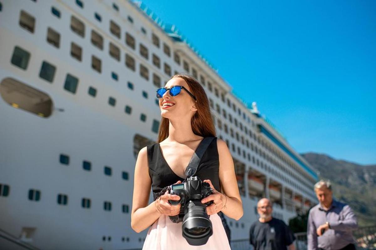 uma mulher segurando uma câmera em frente a um navio de cruzeiro