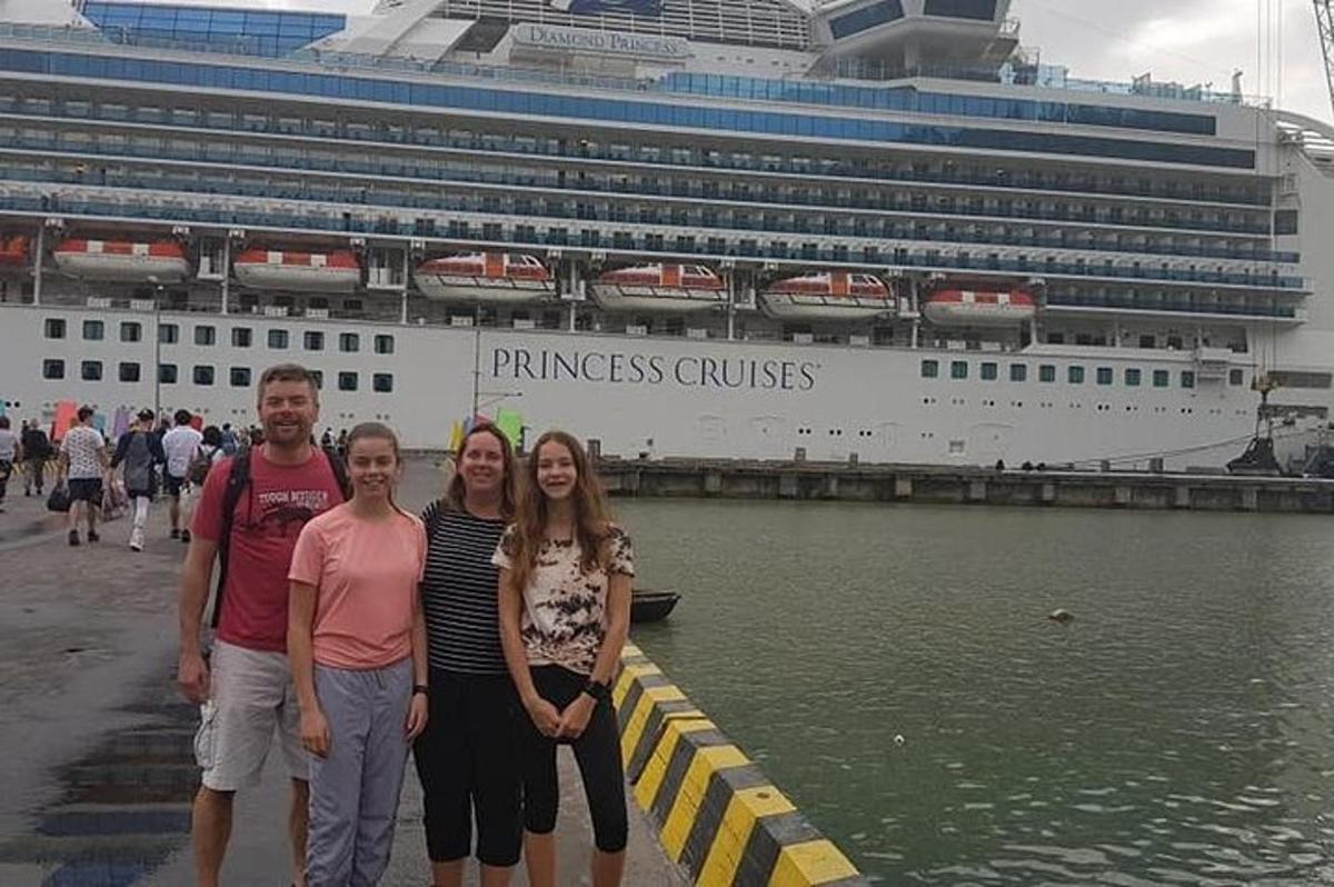 un gruppo di persone in piedi davanti a una nave da crociera