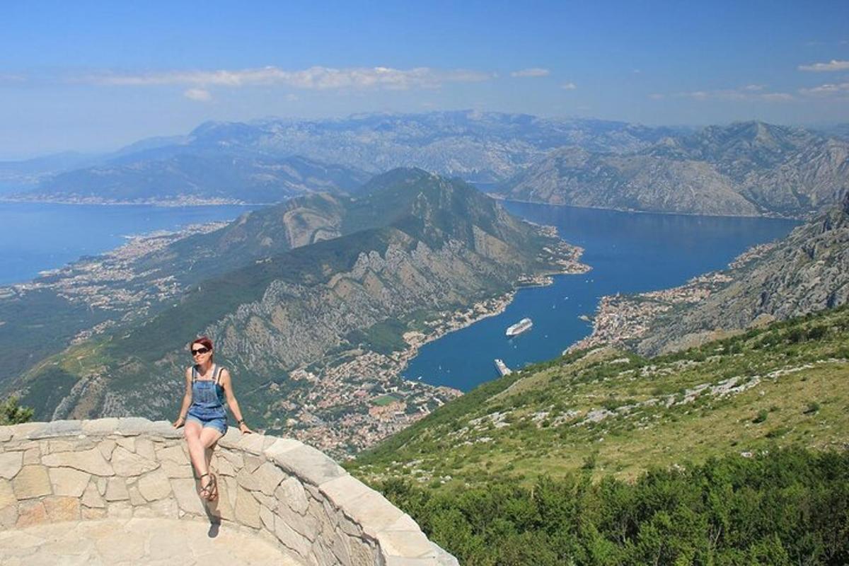 žena sedící na okraji skalní římsy s výhledem na oceán