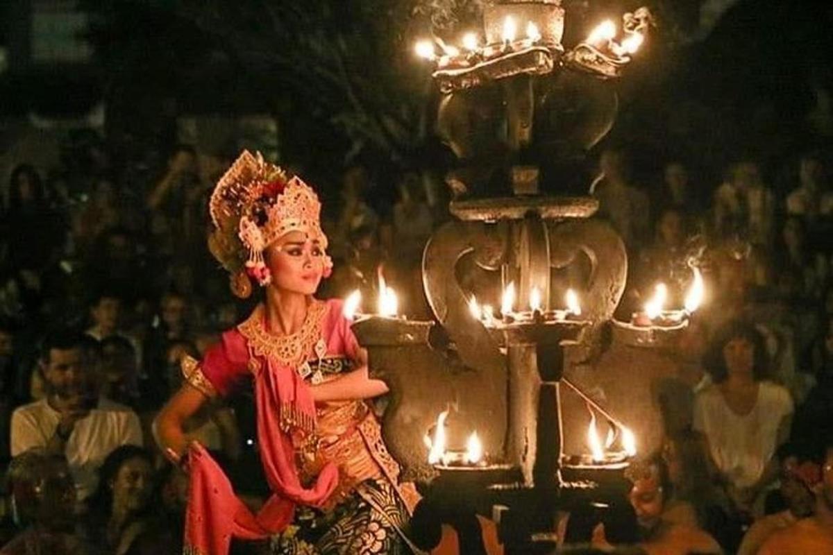 Una mujer caminando frente a una multitud con velas.