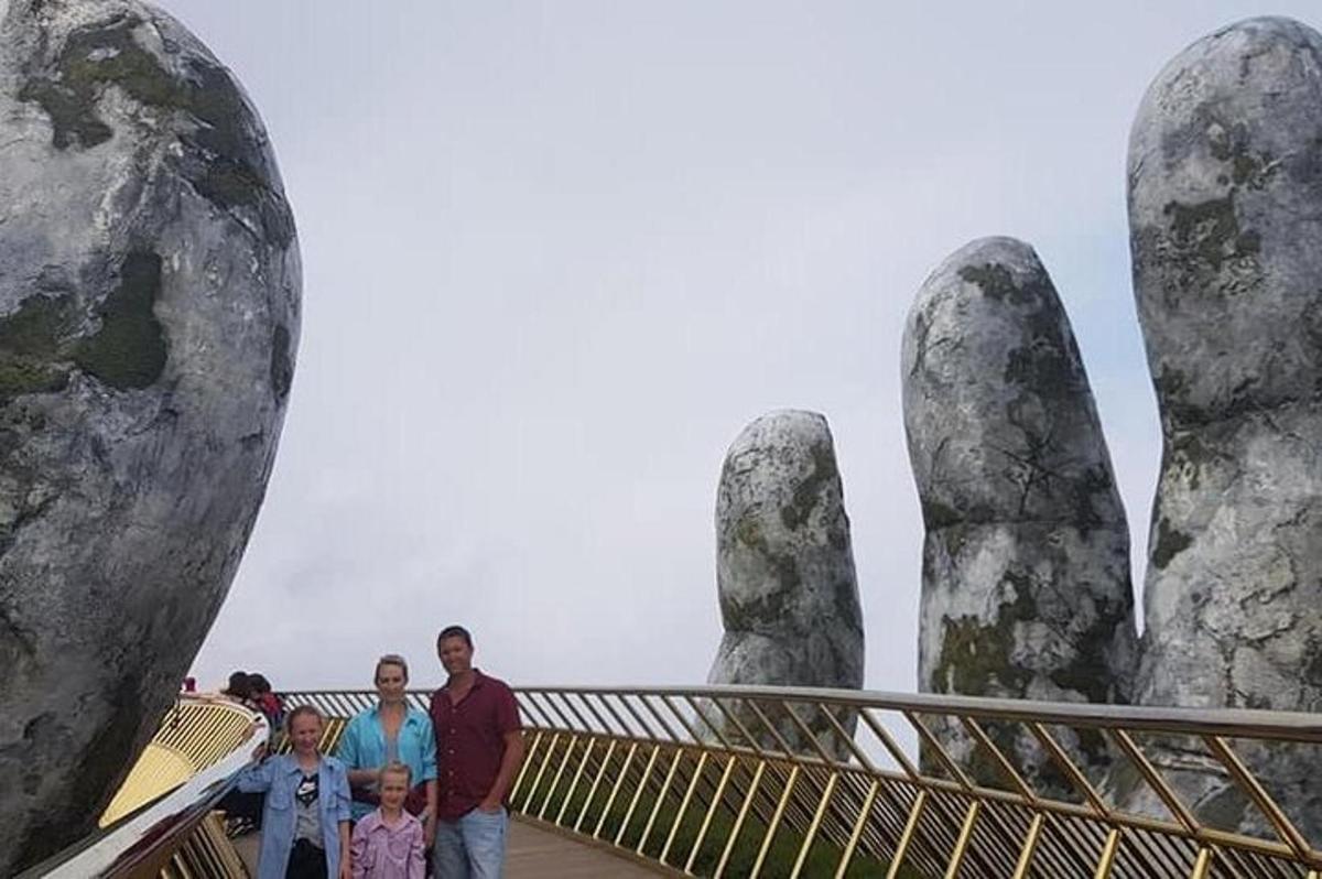 skupina lidí stojící před třemi velkými kamennými rukama