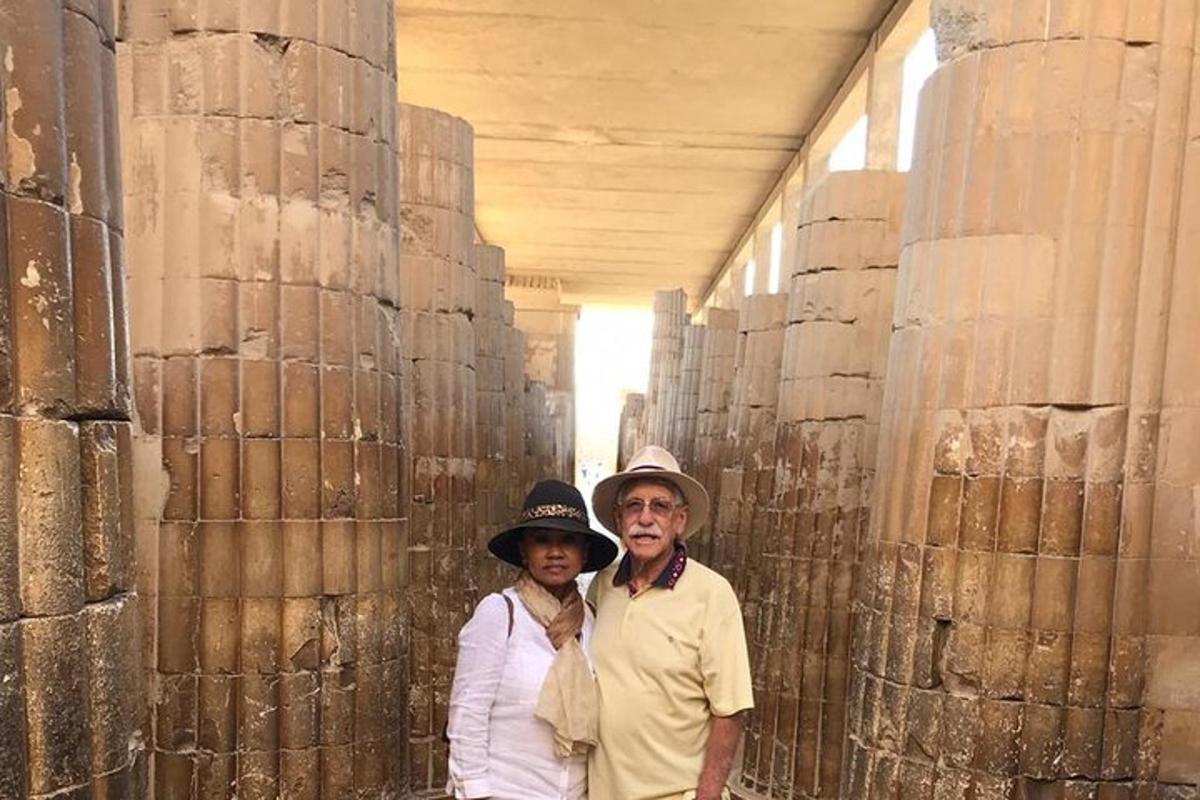 a man and a woman standing in a hallway next to columns