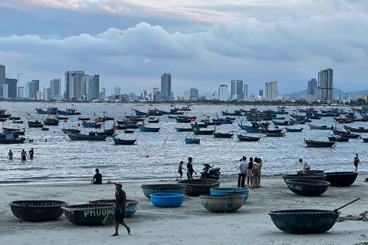 um grupo de pessoas em uma praia com barcos na água