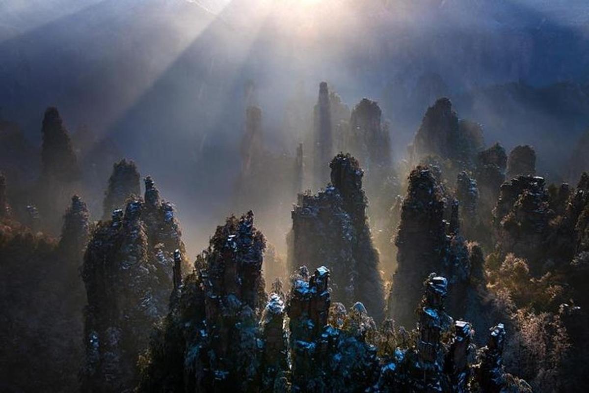 a painting of a mountain with the sun shining on it