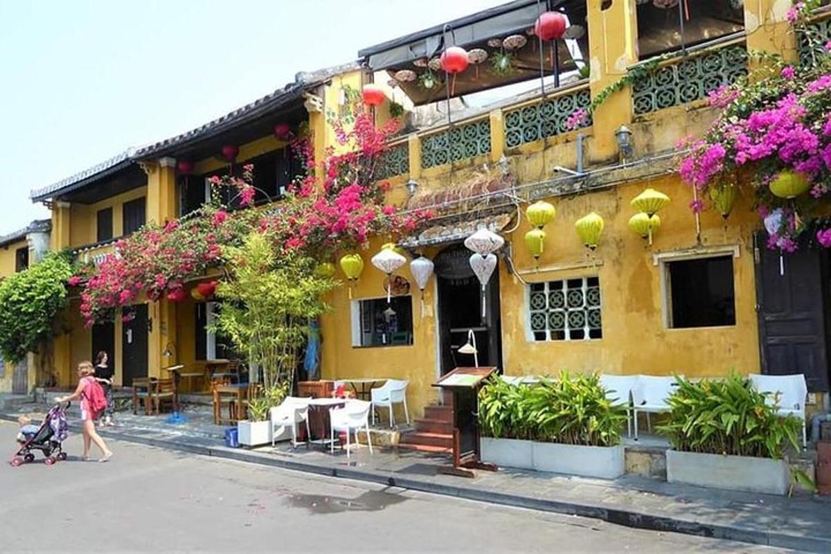 một người phụ nữ đang đi trước một tòa nhà màu vàng có hoa