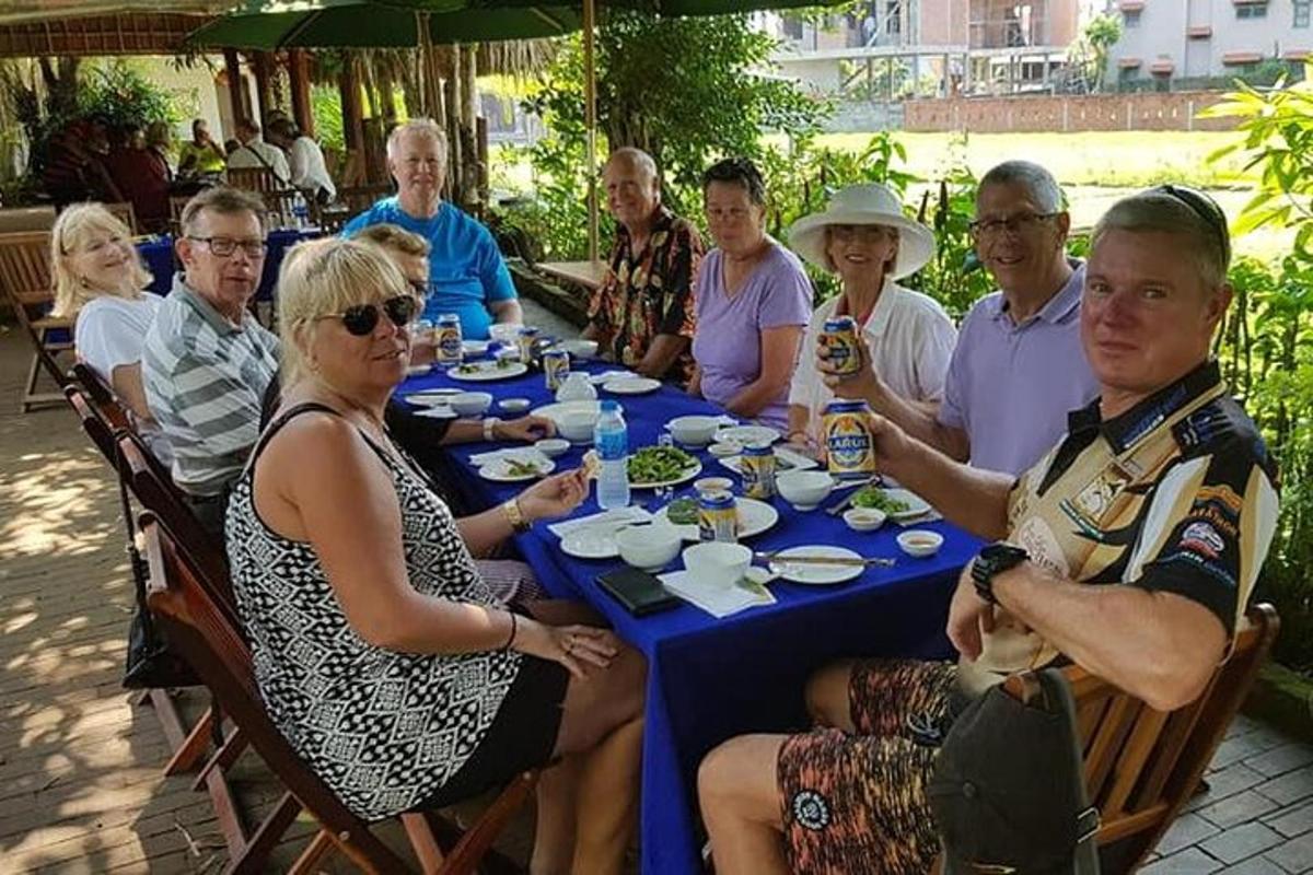 een groep mensen die rond een tafel zitten en eten