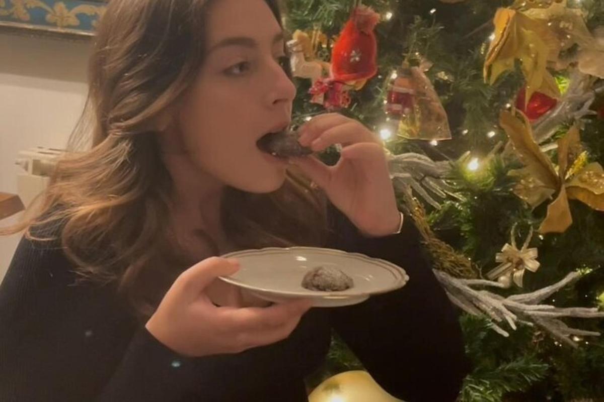 一位女士在圣诞树旁吃着盘子里的食物