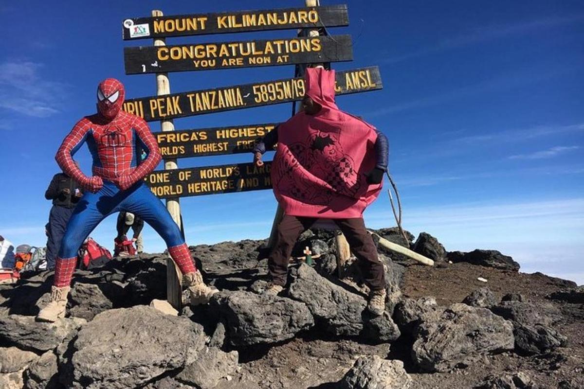 tiga orang berdiri di puncak gunung dengan sebuah tanda