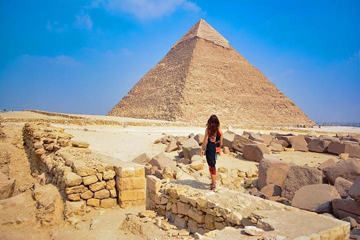a woman standing on a wall in front of the pyramids
