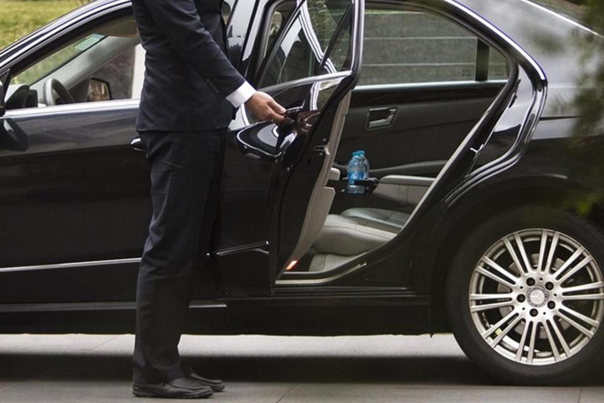 iš automobilio išlipantis vyras su kostiumu