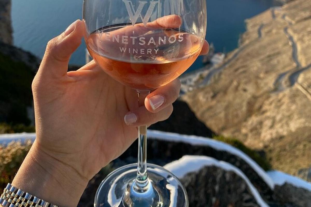 uma pessoa segurando uma taça de vinho em frente a uma montanha