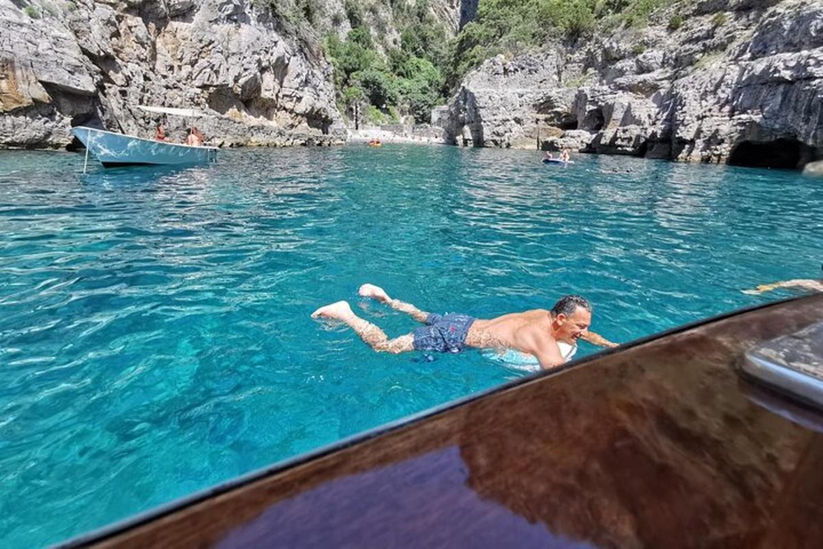 човек лежи у води поред чамца