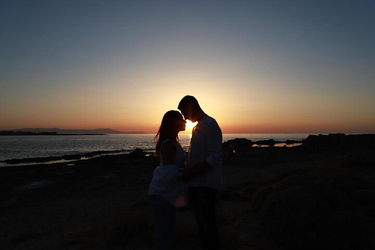 a man and woman standing on the beach at sunset