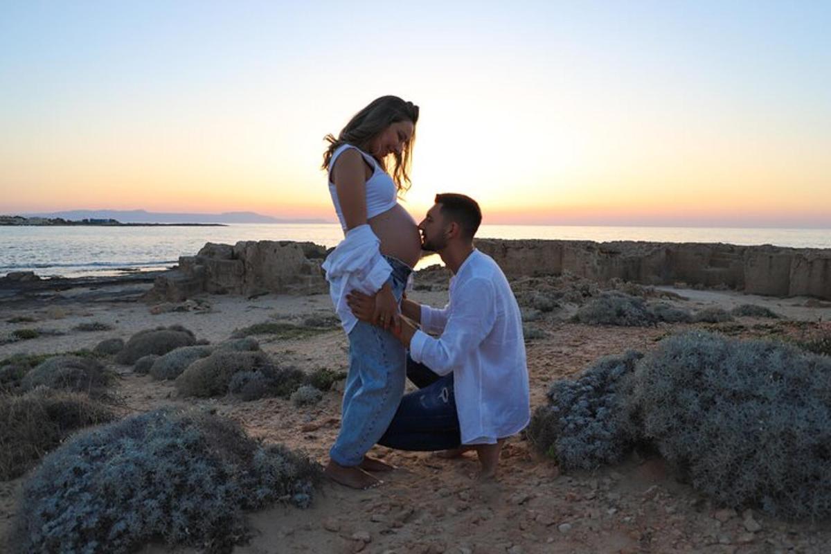 un uomo che tiene in braccio una donna incinta sulla spiaggia