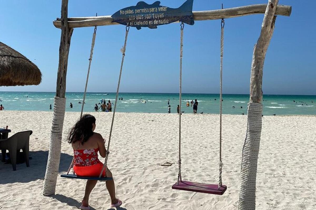 una mujer sentada en un columpio en la playa