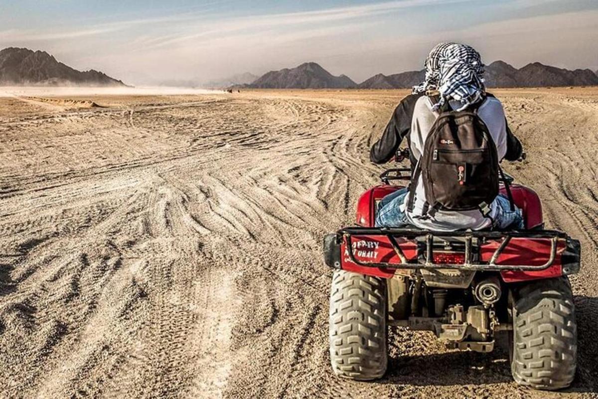 uma pessoa andando de quadriciclo no deserto