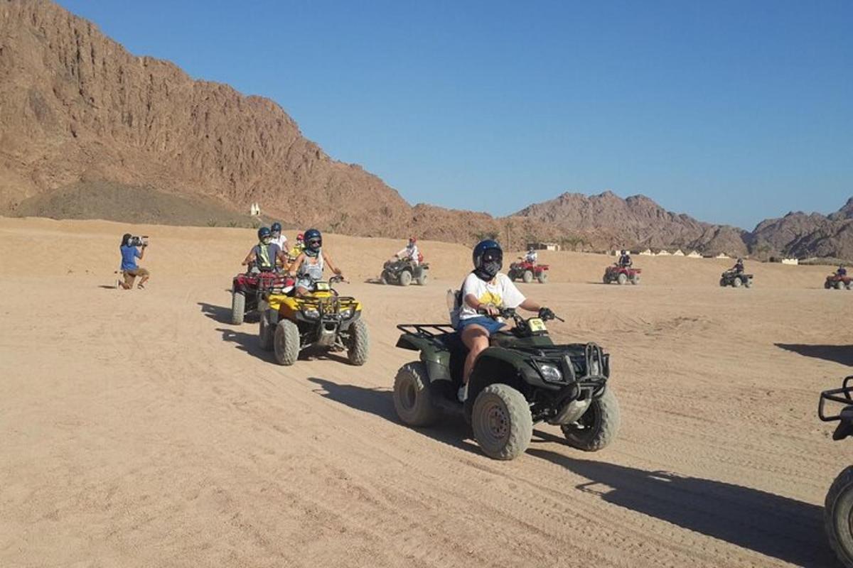 um grupo de pessoas andando de quadriciclo no deserto