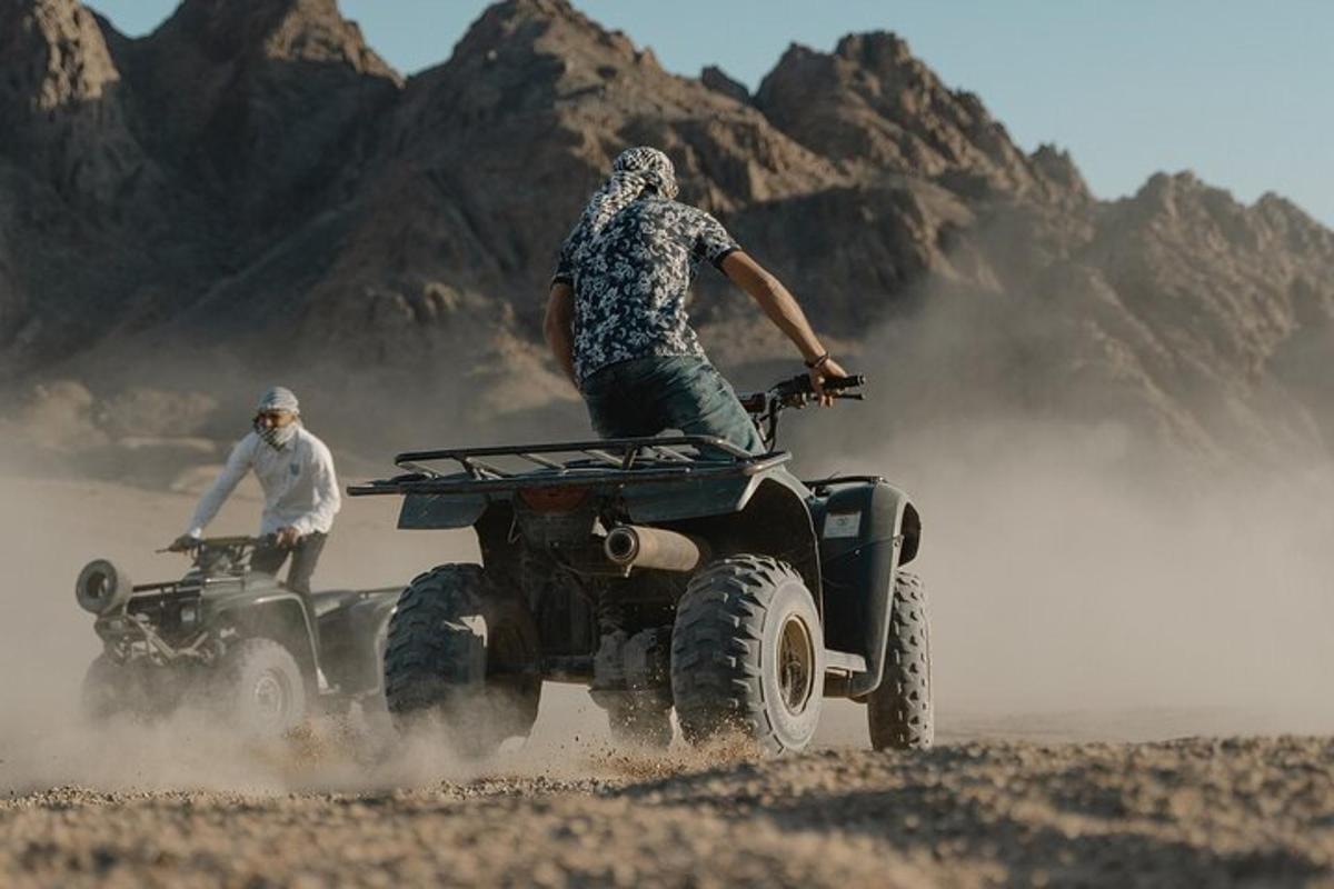 dois homens andando de quadriciclo no deserto