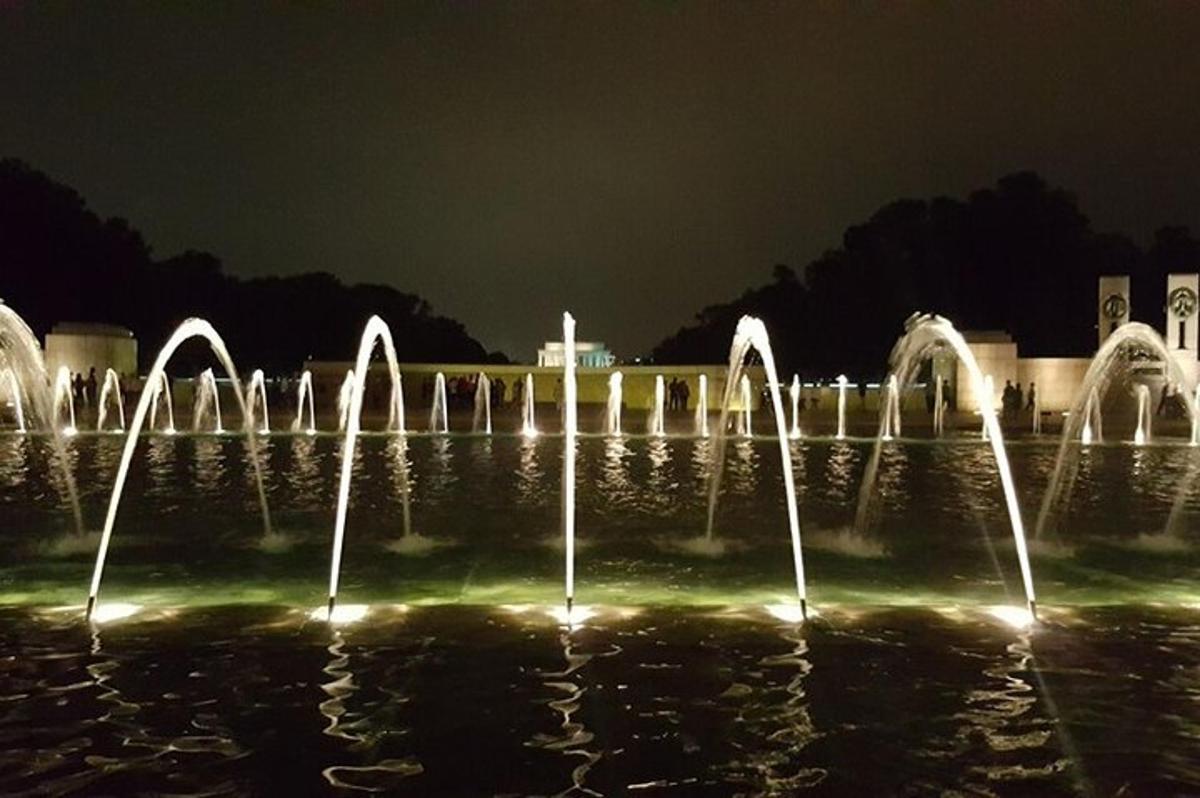 um grupo de fontes de água iluminadas à noite