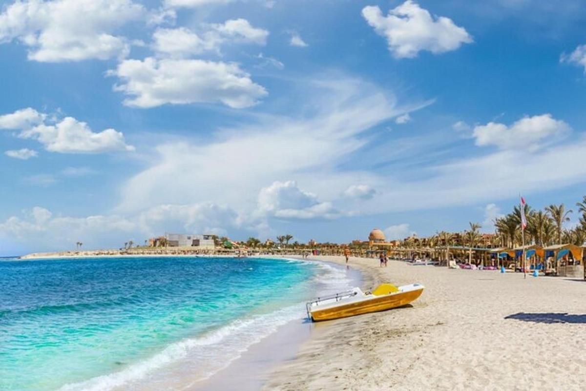a yellow boat sitting on a beach next to the ocean