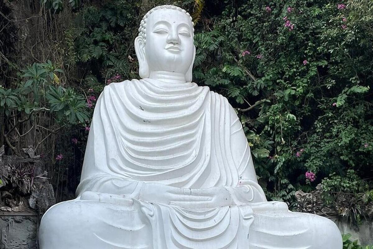 a large white statue sitting in a garden