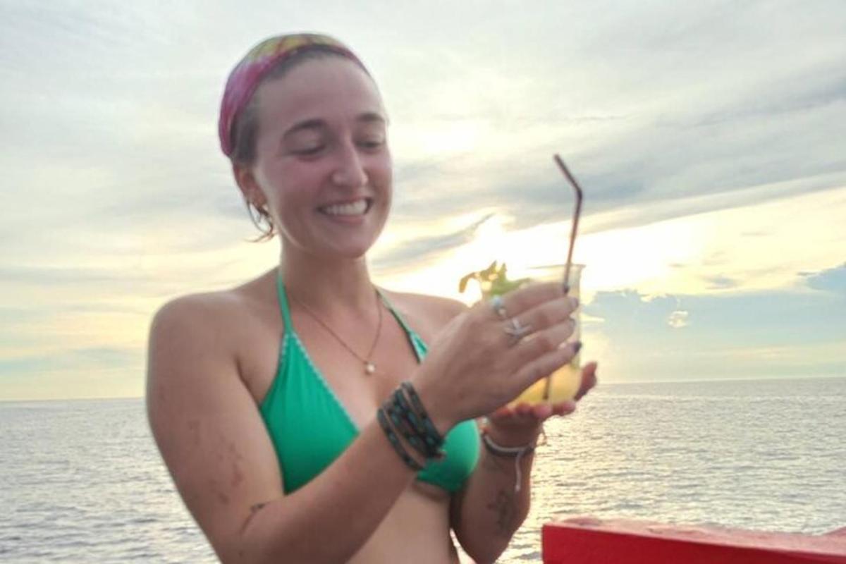 a woman in a green bikini holding a bunch of fruit