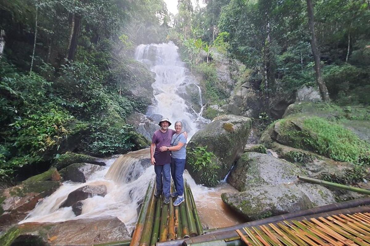 a man and woman standing on a bridge in front of a waterfall