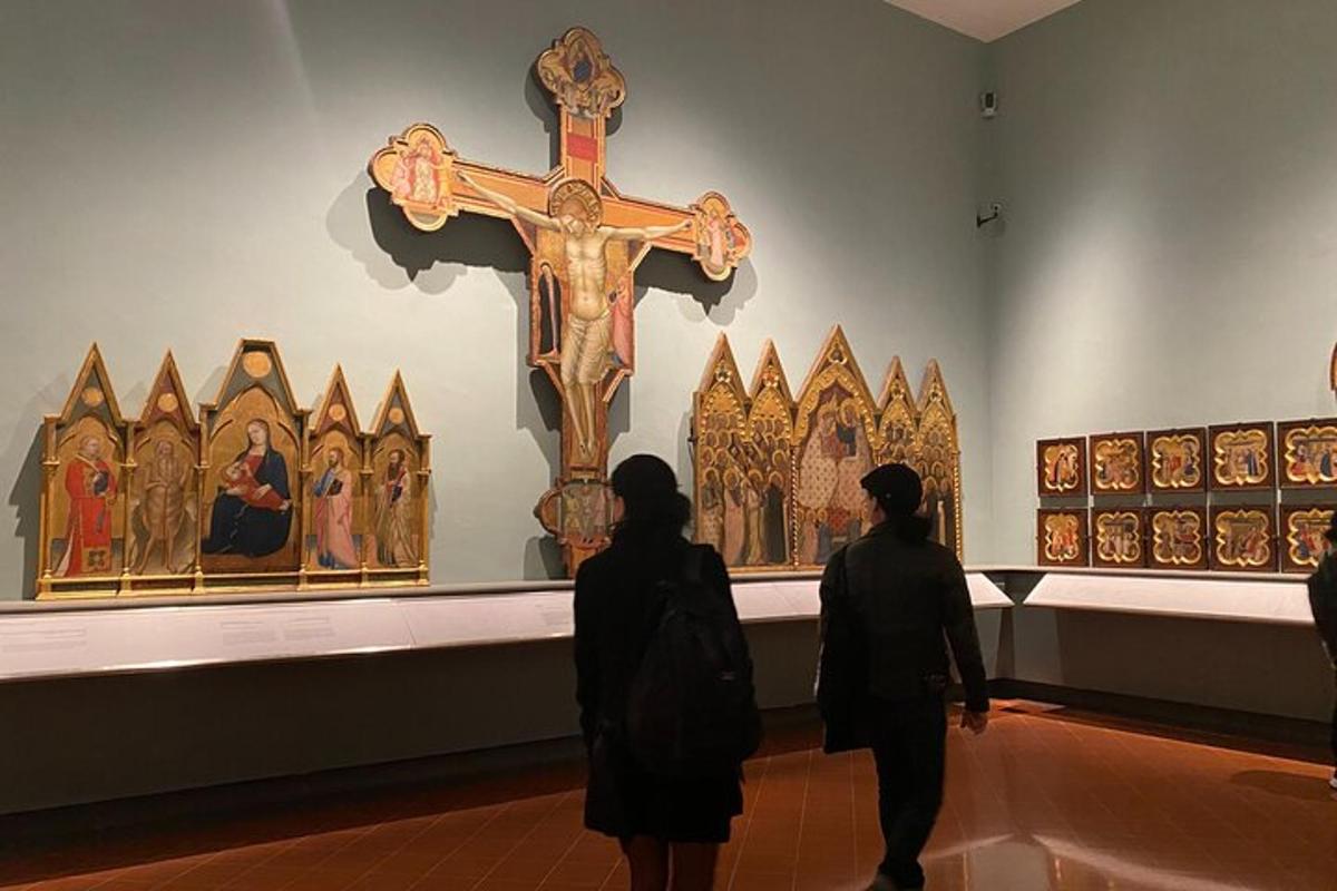 twee mensen kijken naar een kruis dat in een museum wordt tentoongesteld